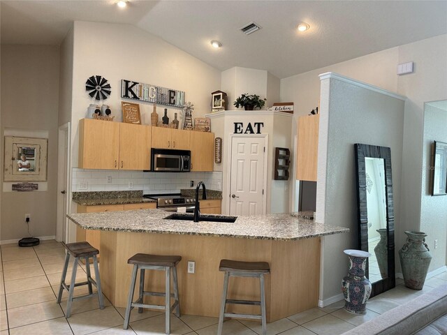 kitchen featuring kitchen peninsula, tasteful backsplash, vaulted ceiling, sink, and appliances with stainless steel finishes