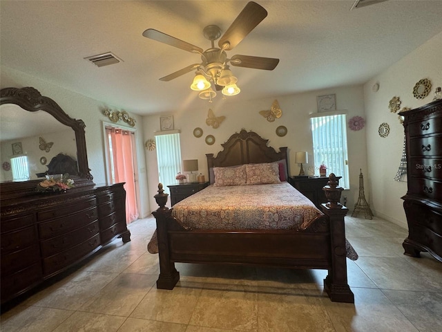 bedroom featuring a textured ceiling, ceiling fan, and tile floors