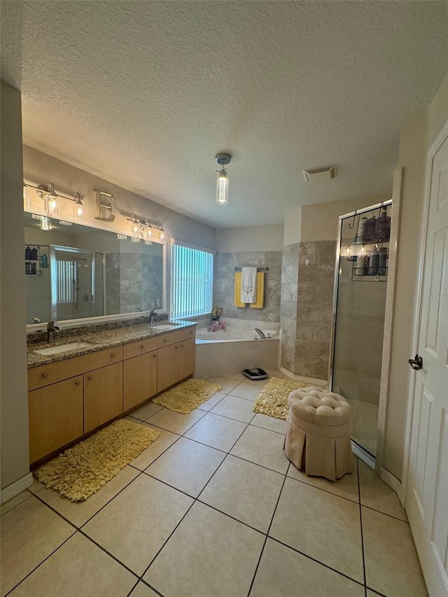 bathroom with dual bowl vanity, tile flooring, a textured ceiling, and separate shower and tub