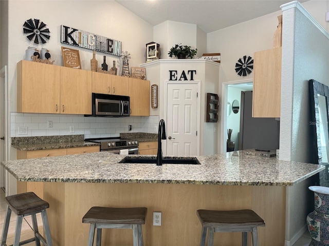 kitchen featuring kitchen peninsula, stainless steel appliances, a kitchen breakfast bar, backsplash, and sink