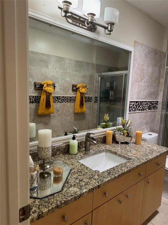 bathroom with tile walls, tile flooring, toilet, and oversized vanity