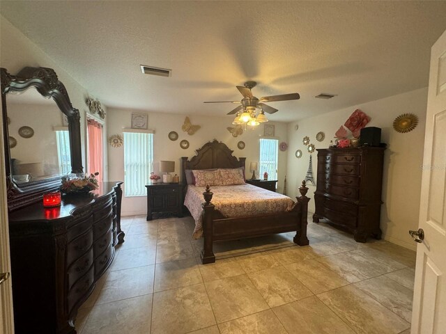 tiled bedroom with ceiling fan, a textured ceiling, and multiple windows