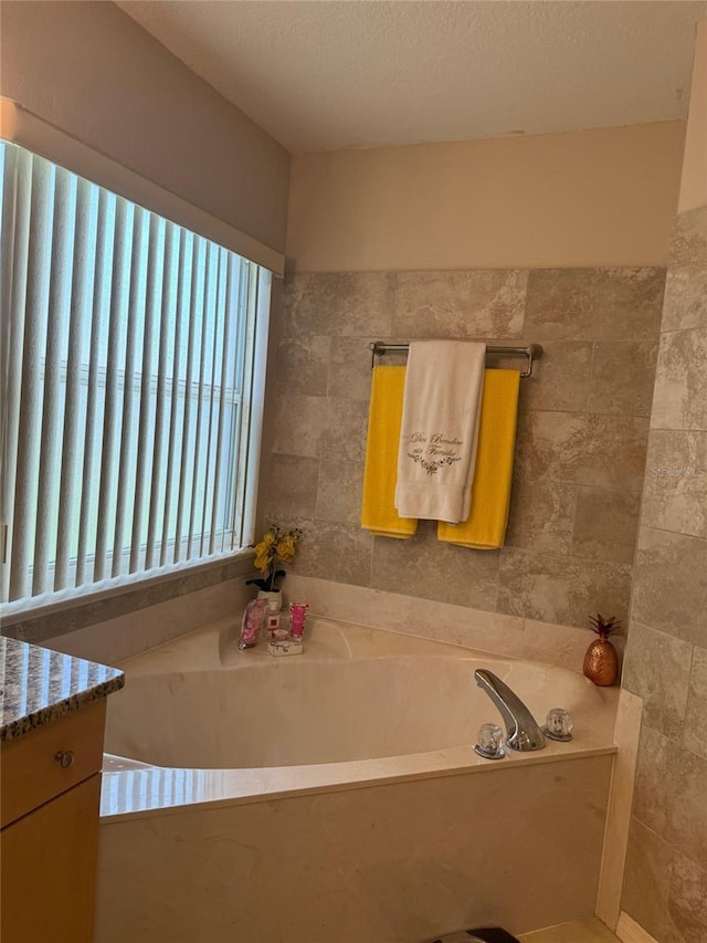 bathroom with a textured ceiling, a bathing tub, and vanity