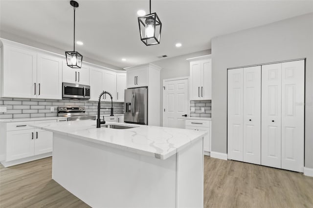 kitchen with a center island with sink, decorative light fixtures, and appliances with stainless steel finishes