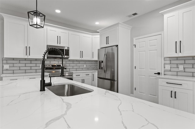 kitchen featuring tasteful backsplash, light stone countertops, hanging light fixtures, and appliances with stainless steel finishes