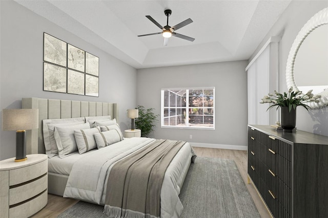 bedroom with a tray ceiling, ceiling fan, and light hardwood / wood-style floors