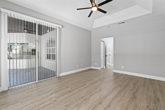 empty room featuring hardwood / wood-style flooring, ceiling fan, and a tray ceiling