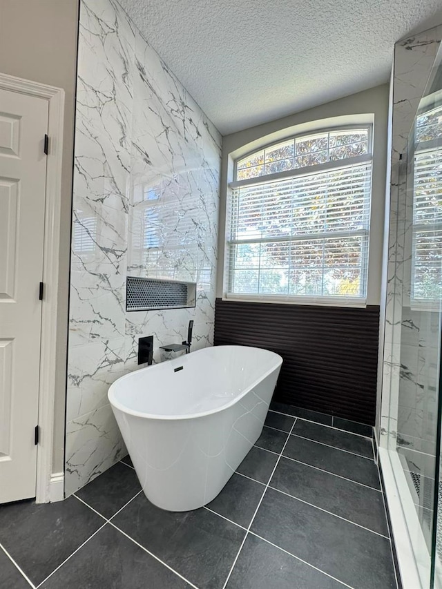 bathroom with tile patterned floors, tile walls, plus walk in shower, and a textured ceiling