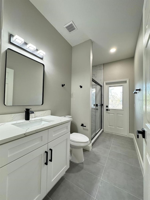 bathroom with tile patterned flooring, vanity, toilet, and an enclosed shower