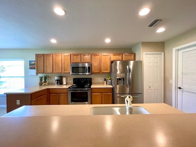 kitchen with appliances with stainless steel finishes, a textured ceiling, and sink