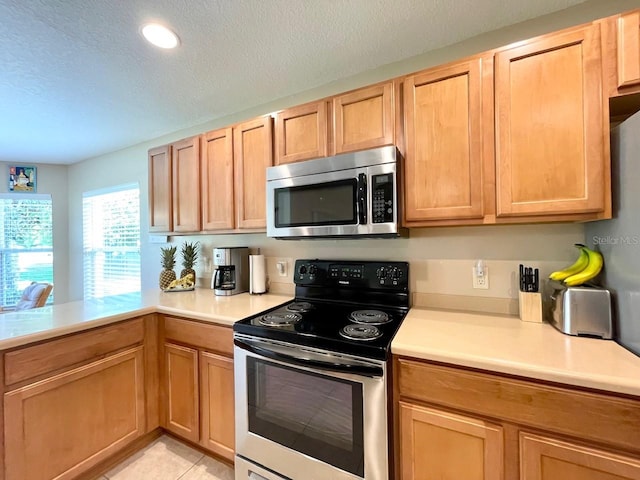 kitchen with electric range, a textured ceiling, and light tile patterned floors