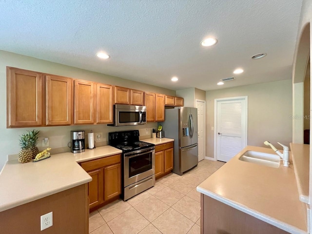 kitchen featuring light tile patterned flooring, stainless steel appliances, sink, and a textured ceiling