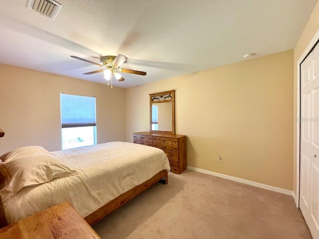 bedroom featuring a textured ceiling, a closet, carpet, and ceiling fan