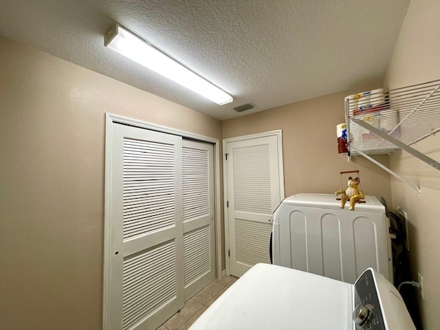 laundry area featuring light tile patterned flooring, washer / clothes dryer, and a textured ceiling