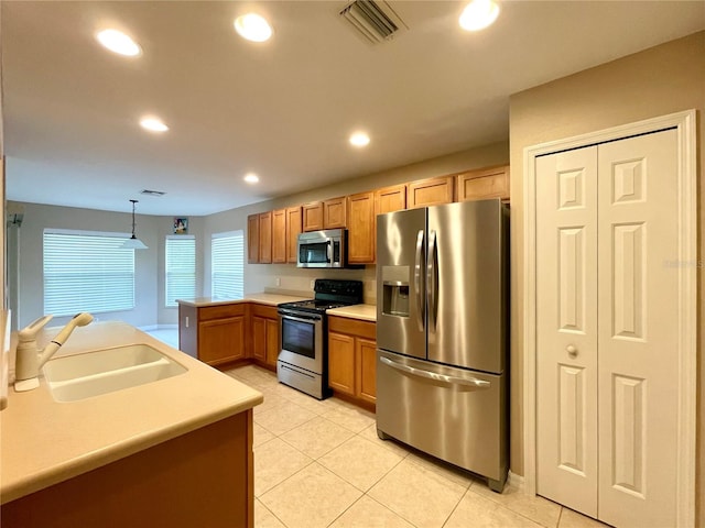 kitchen with stainless steel appliances, sink, kitchen peninsula, decorative light fixtures, and light tile patterned floors