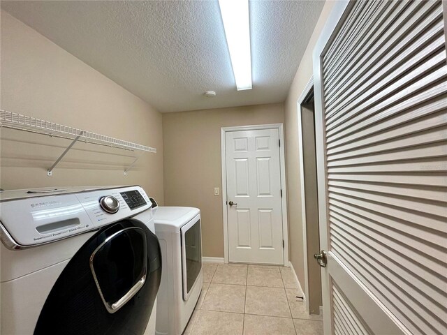 laundry room with washer and dryer, a textured ceiling, and light tile patterned floors