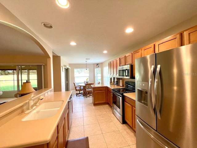 kitchen with appliances with stainless steel finishes, light tile patterned floors, pendant lighting, and sink