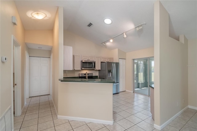 kitchen with kitchen peninsula, stainless steel appliances, vaulted ceiling, light tile flooring, and track lighting