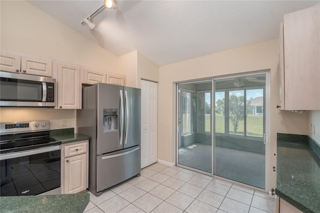 kitchen featuring track lighting, appliances with stainless steel finishes, light tile floors, and lofted ceiling