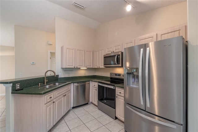 kitchen featuring appliances with stainless steel finishes, kitchen peninsula, sink, track lighting, and light tile floors