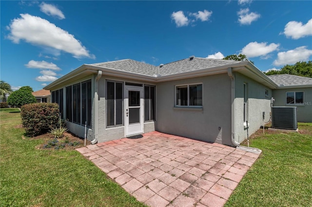 back of property with a sunroom, a patio area, a yard, and central air condition unit