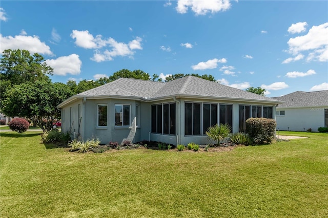 back of property with a sunroom and a lawn