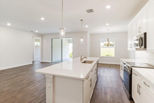 kitchen featuring white cabinets, an island with sink, hanging light fixtures, and appliances with stainless steel finishes