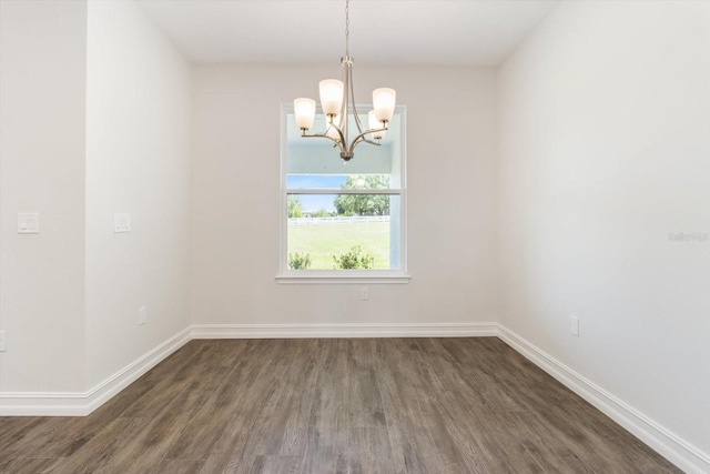 spare room featuring an inviting chandelier and dark wood-type flooring