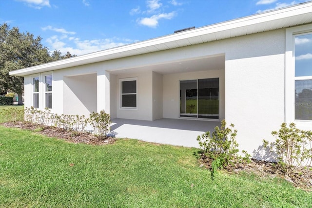 back of house featuring a lawn and a patio area