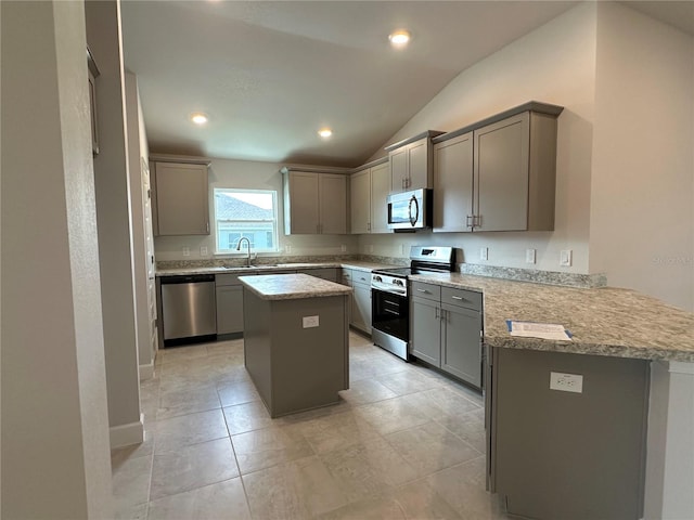 kitchen with lofted ceiling, a center island, kitchen peninsula, appliances with stainless steel finishes, and gray cabinets