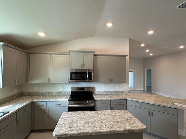 kitchen with light stone counters, gray cabinets, stainless steel appliances, and vaulted ceiling