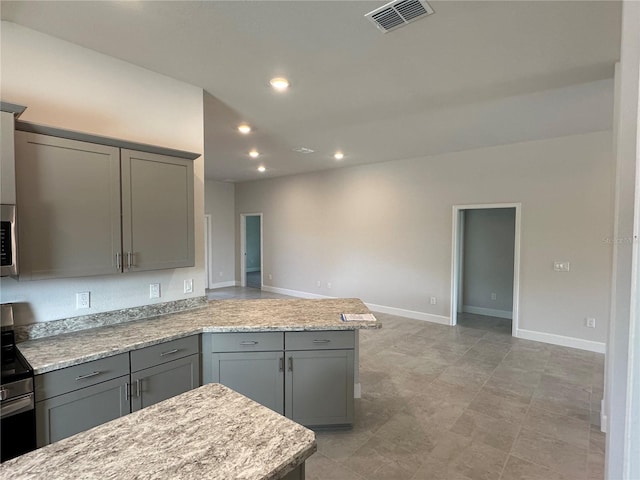 kitchen featuring gray cabinets, light stone countertops, and stainless steel appliances