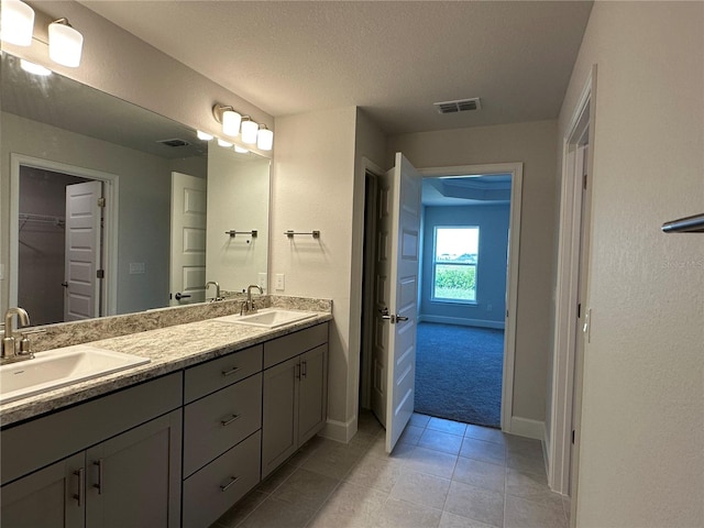 bathroom with tile patterned floors, vanity, and a textured ceiling