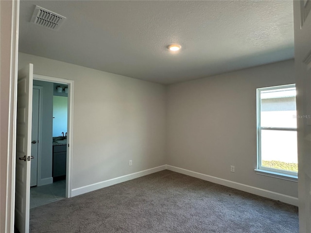 carpeted empty room featuring a textured ceiling