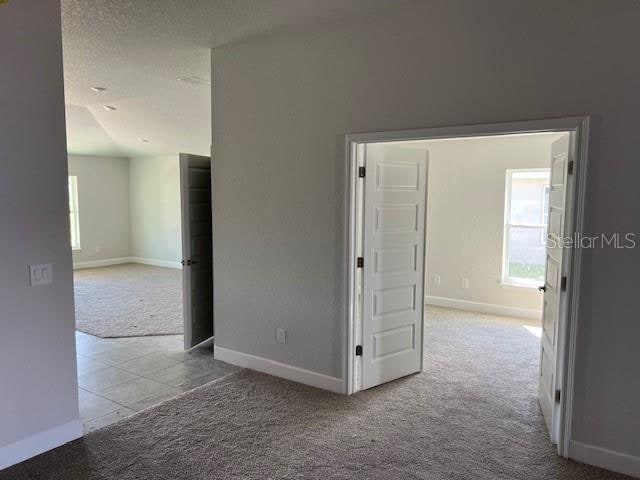 empty room with a textured ceiling and light colored carpet