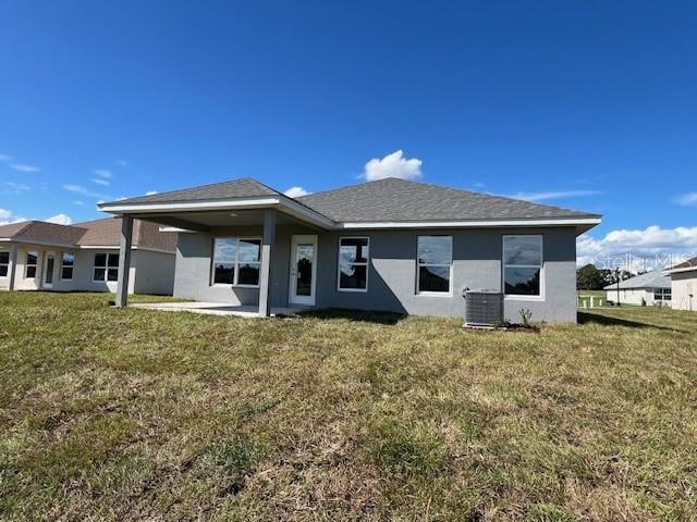 back of property featuring a lawn and central AC