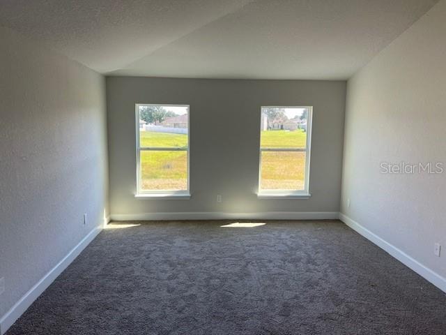 unfurnished room featuring dark colored carpet