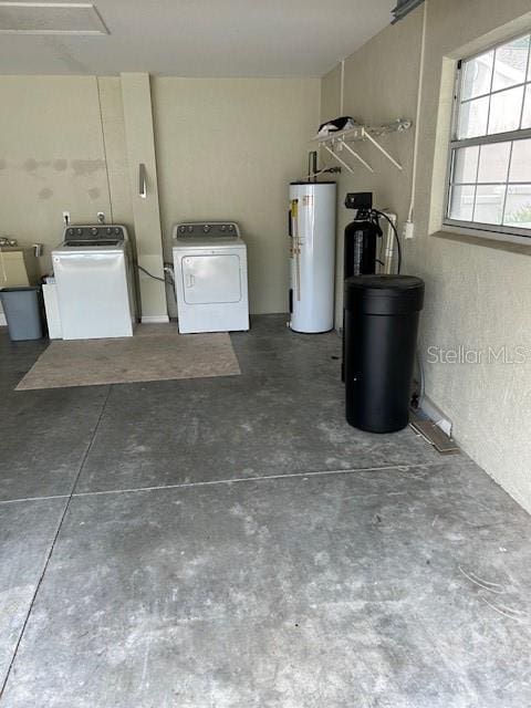 garage featuring electric water heater and washing machine and clothes dryer