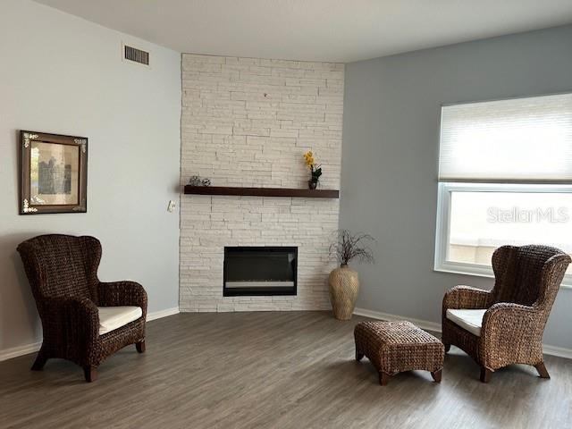 living area featuring a stone fireplace and dark wood-type flooring