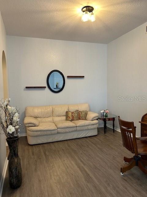 living room with dark wood-type flooring and a textured ceiling