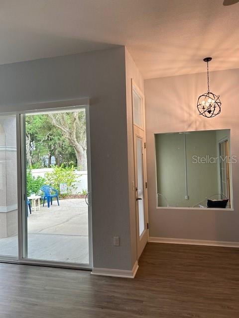 doorway to outside with dark hardwood / wood-style flooring and a chandelier