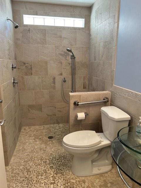 bathroom featuring toilet, tile walls, and a tile shower