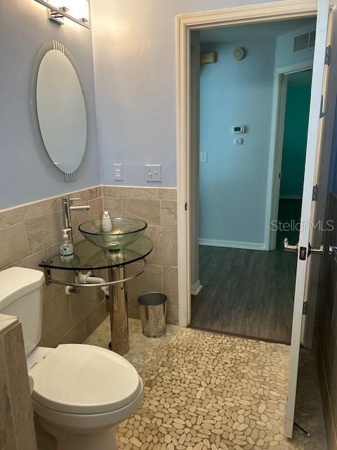 bathroom featuring tile walls, sink, and toilet