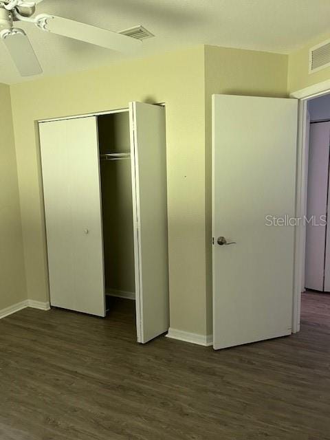 unfurnished bedroom featuring ceiling fan, dark hardwood / wood-style flooring, and a closet