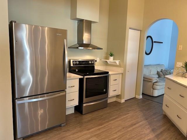 kitchen with white cabinetry, appliances with stainless steel finishes, dark hardwood / wood-style floors, and wall chimney range hood