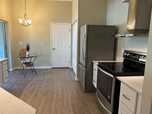 kitchen featuring pendant lighting, electric range, dark hardwood / wood-style floors, extractor fan, and white cabinets