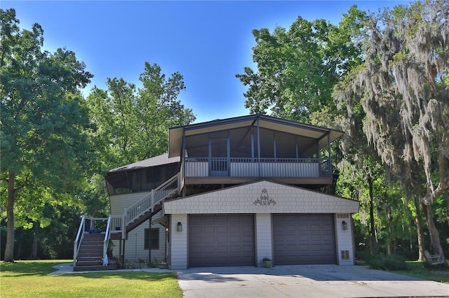 view of front of property featuring a front lawn, a garage, and a sunroom