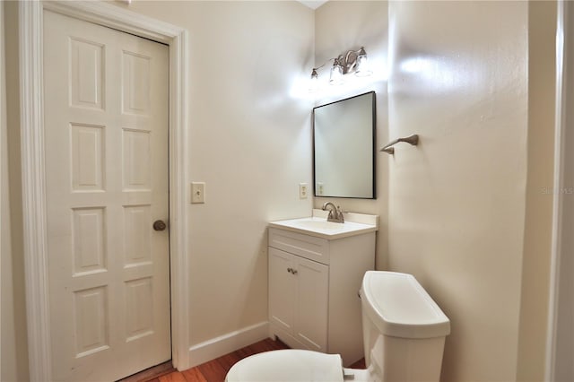 bathroom with wood-type flooring, vanity, and toilet