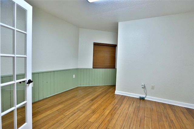 unfurnished room with hardwood / wood-style flooring and a textured ceiling