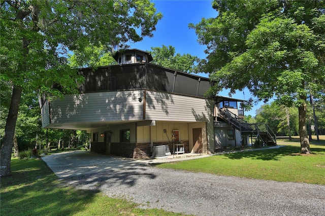 view of front of house with a carport, central air condition unit, and a front lawn